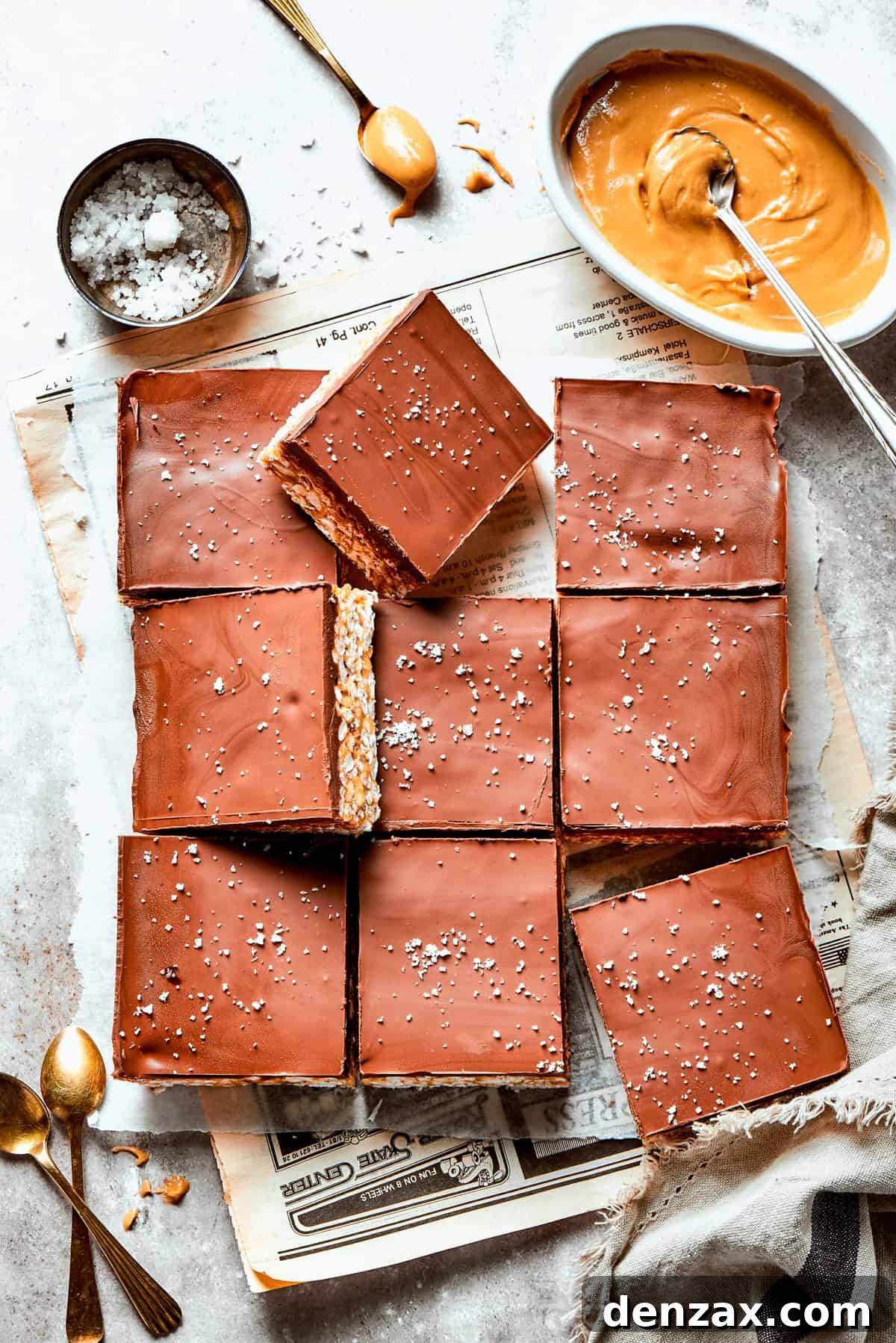 Cut into bars Rice crispy treats cut into squares with a bowl of peanut butter and a bowl of salt nearby.