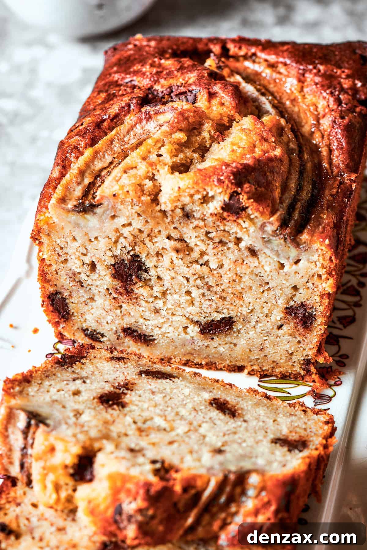 Close-up image of a cut sour cream banana bread with the interior exposed to see the texture and chocolate chips.
