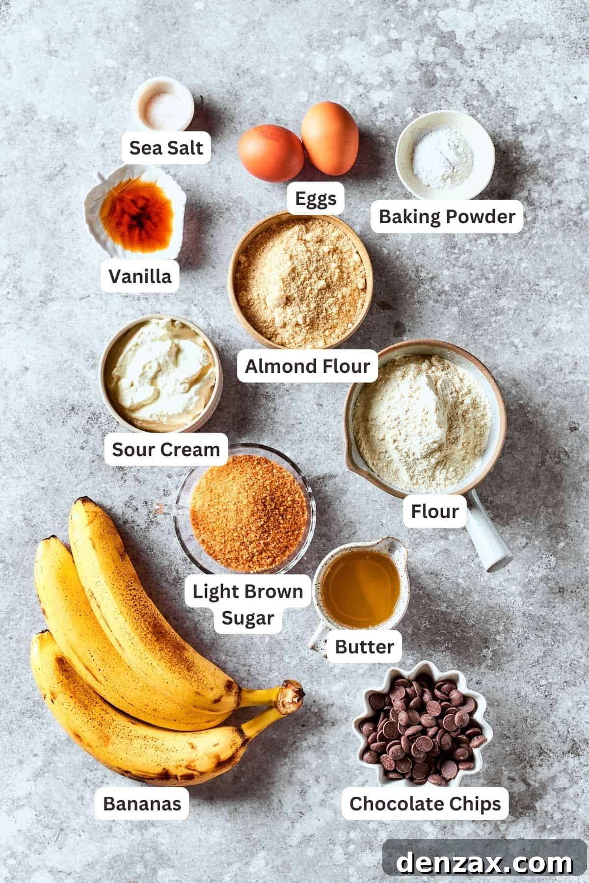 Ingredients for sour cream banana bread are labelled and portioned out: bananas, brown sugar, almond flour, sour cream, all-purpose flour, baking powder, eggs, vanilla, salt, chocolate chips, butter.