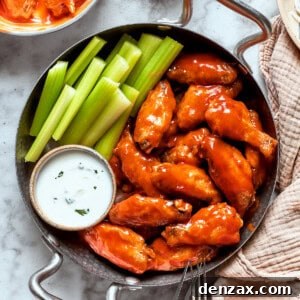 A view of a table holding a towel and a pan with buffalo wings, sauce, and celery.