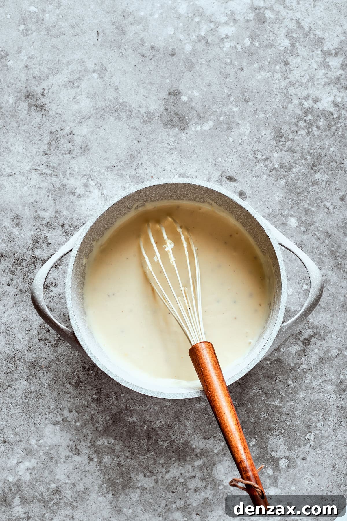 A whisk blends the sauce in a bowl.