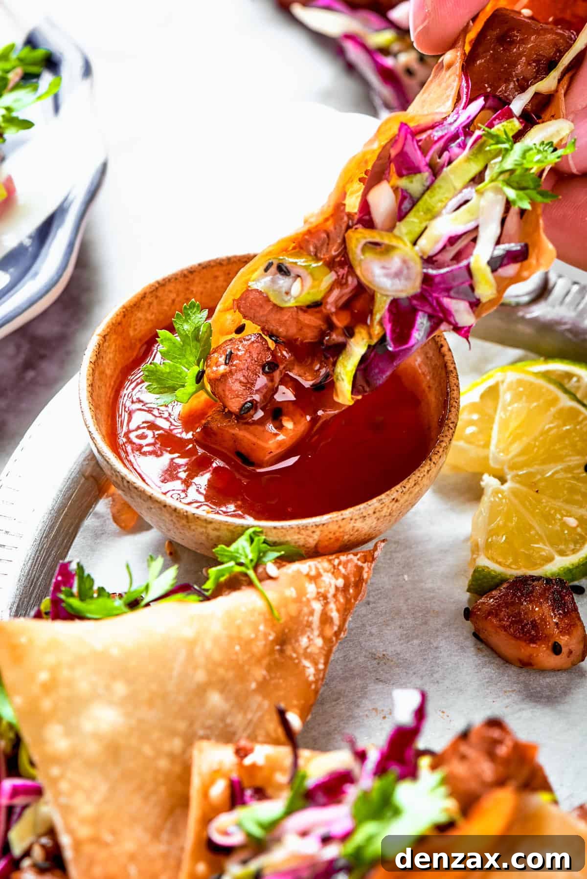 Dipping a taco into a bowl of red sauce.
