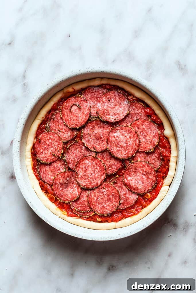 Pepperoni slices are added to the pizza.