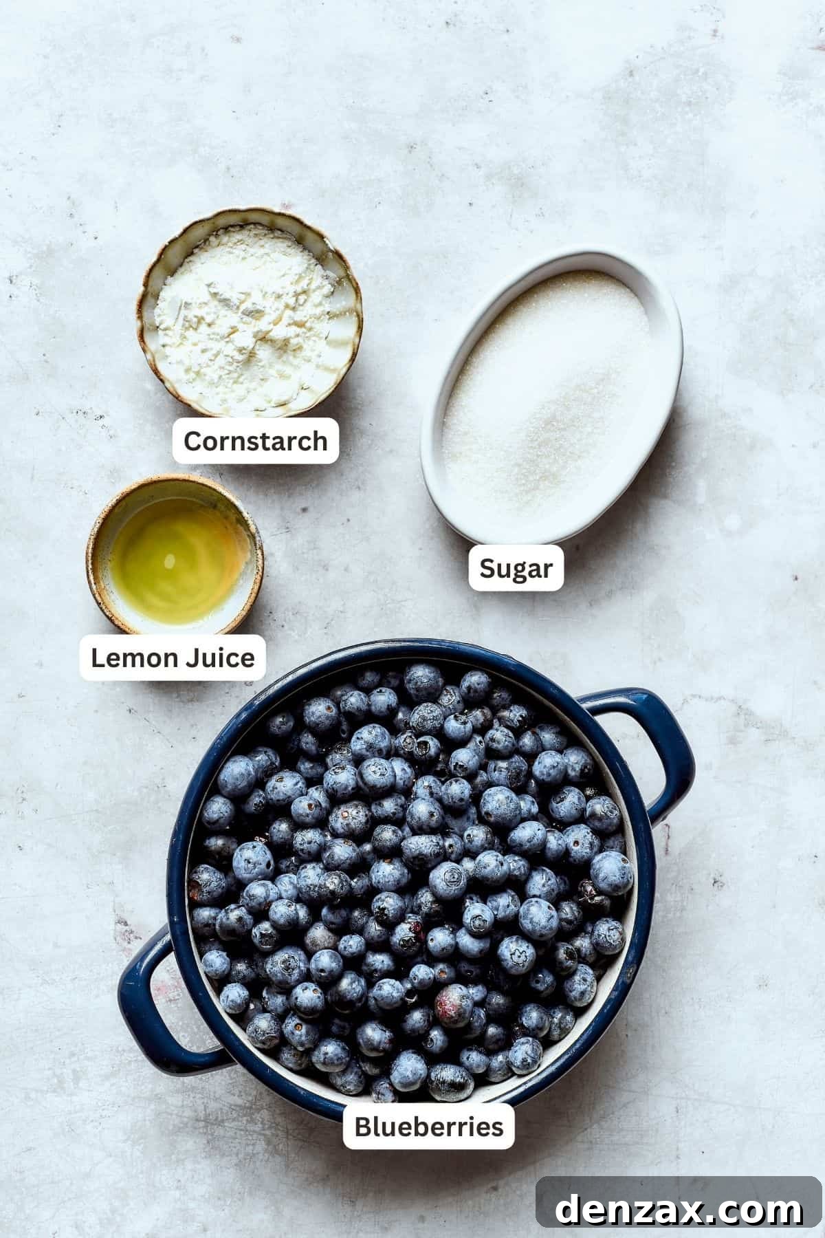 Bursting with juicy berries, this Blueberry Crisp Recipe is topped with a buttery brown sugar and oat crumble. Ingredients for blueberry crisp filling are labeled and portioned: cornstarch, sugar, blueberries, lemon juice.