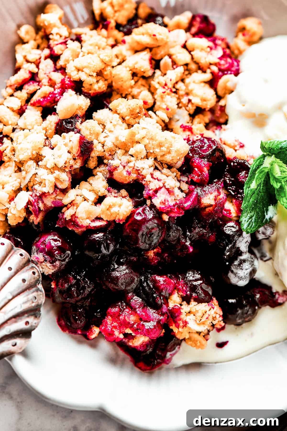 Bursting with juicy berries, this Blueberry Crisp Recipe is topped with a buttery brown sugar and oat crumble. Close-up shot of baked blueberries under a crisp topping.