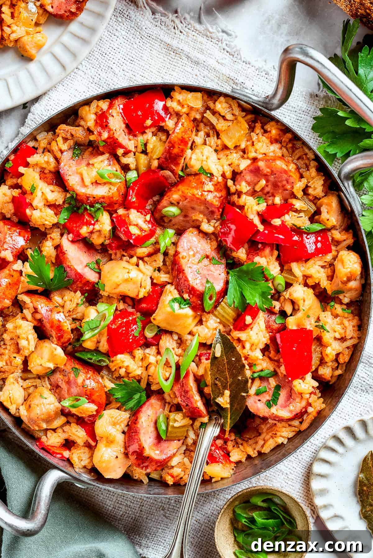Pan of jambalaya with rice, chicken bites, sausage slices, and diced red bell pepper.