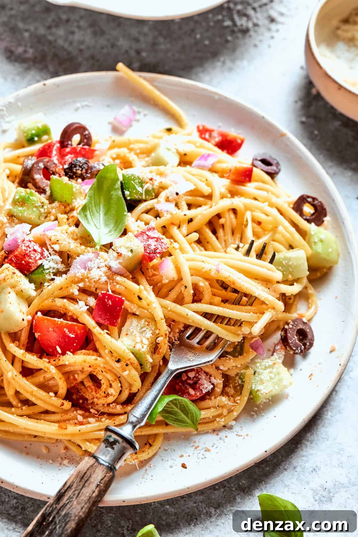 A fork scoops into a plate of spaghetti salad.