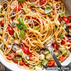 Fresh vegetables are shown in a bowl of spaghetti salad.
