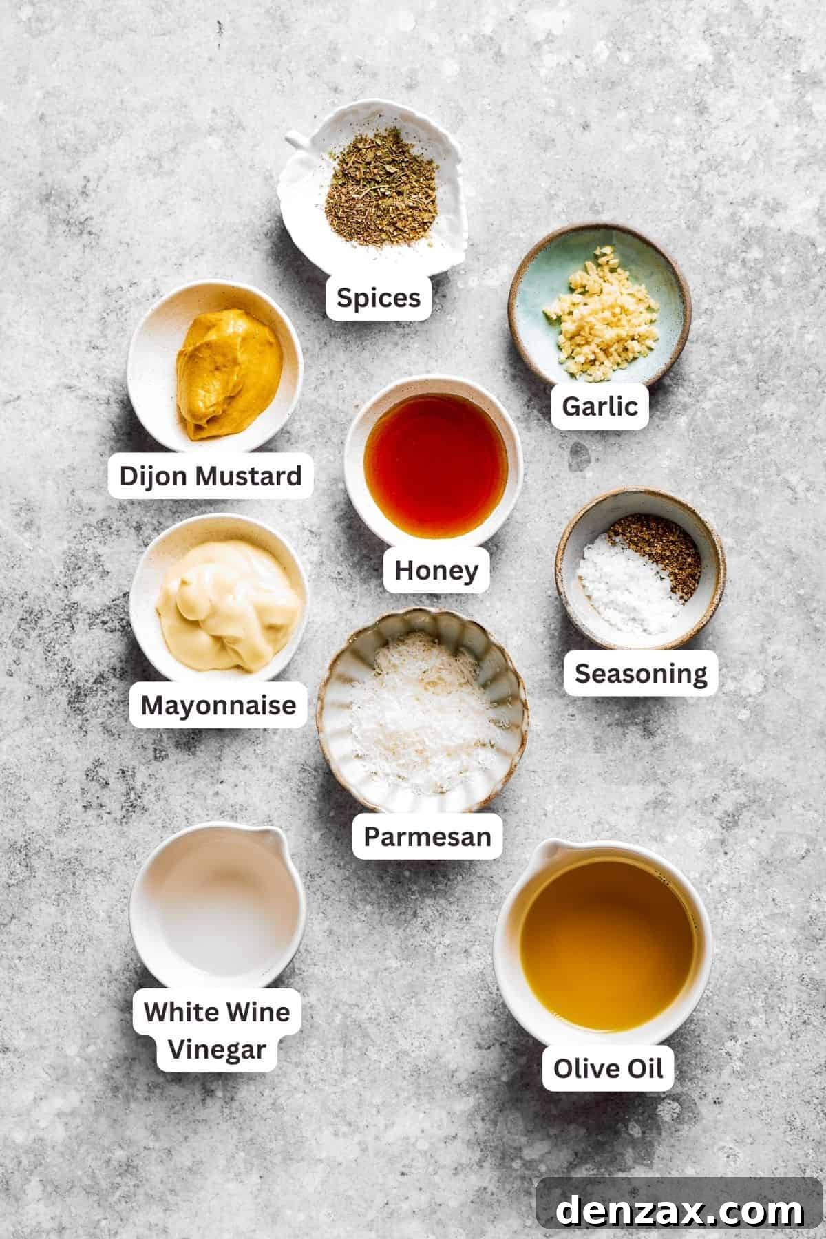 The ingredients for the dressing for spaghetti salad are labeled and portioned: dijon mustard, vinegar, honey, dried herbs, parmesan, mayonnaise, garlic, seasoning salt.