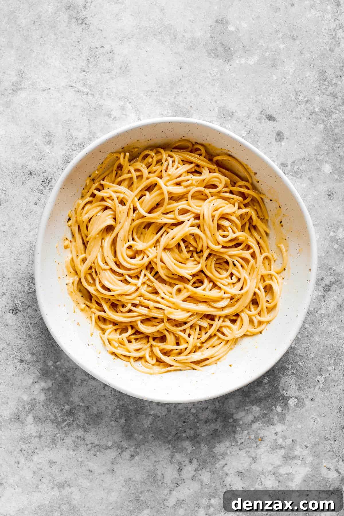 Cooked spaghetti noodles in a white bowl.