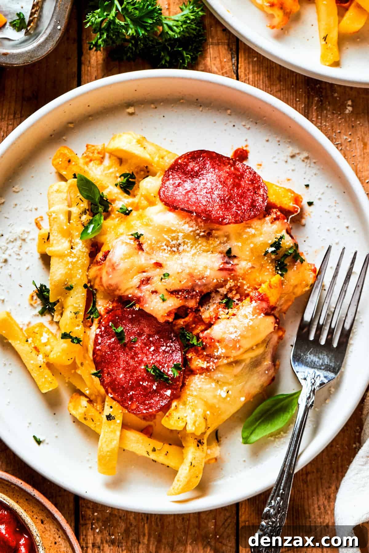 Pizza fries served on a dinner plate with a fork set next to the fries.