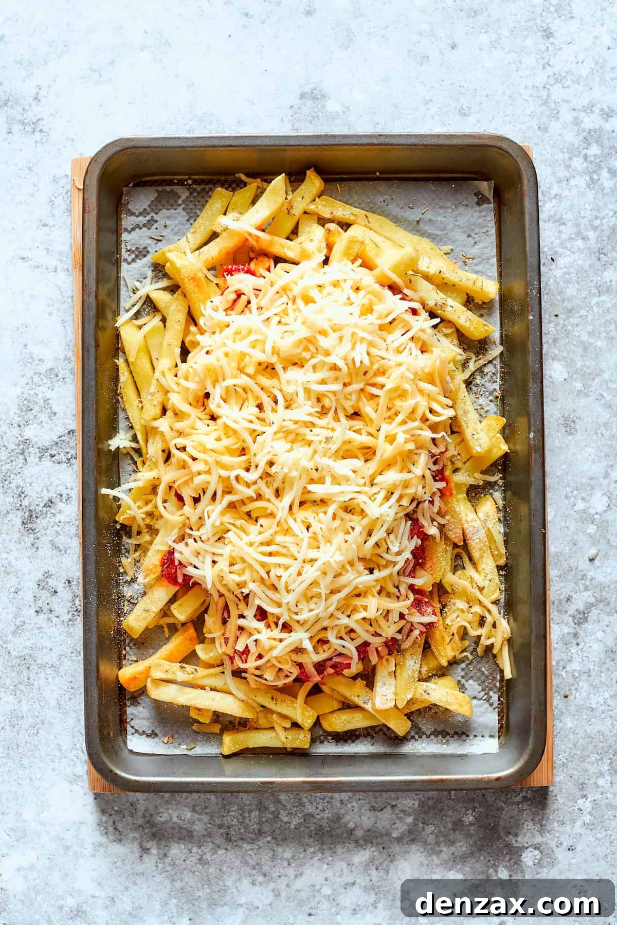 The cheese is added on top of the sauce.