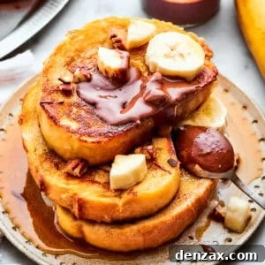 Three slices of French toast stacked topped with banana slices and Nutella.