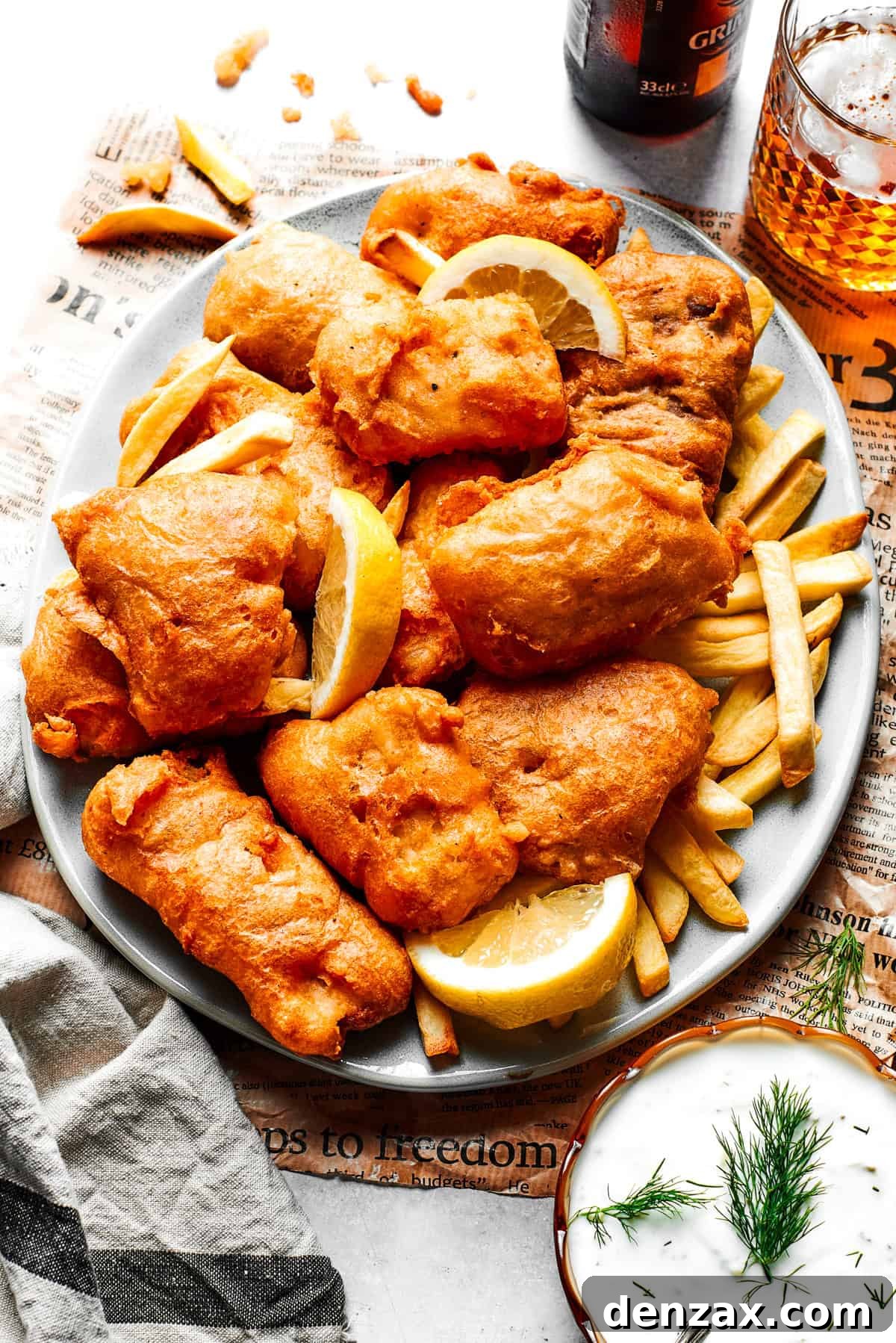Pieces of fried fish are served on a platter over French fries.
