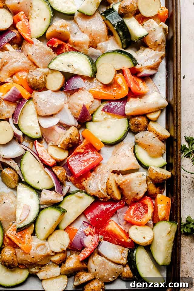 Sheet Pan Chicken with Roasted Vegetables Dinner 3 prepping raw chicken and vegetables on a baking sheet