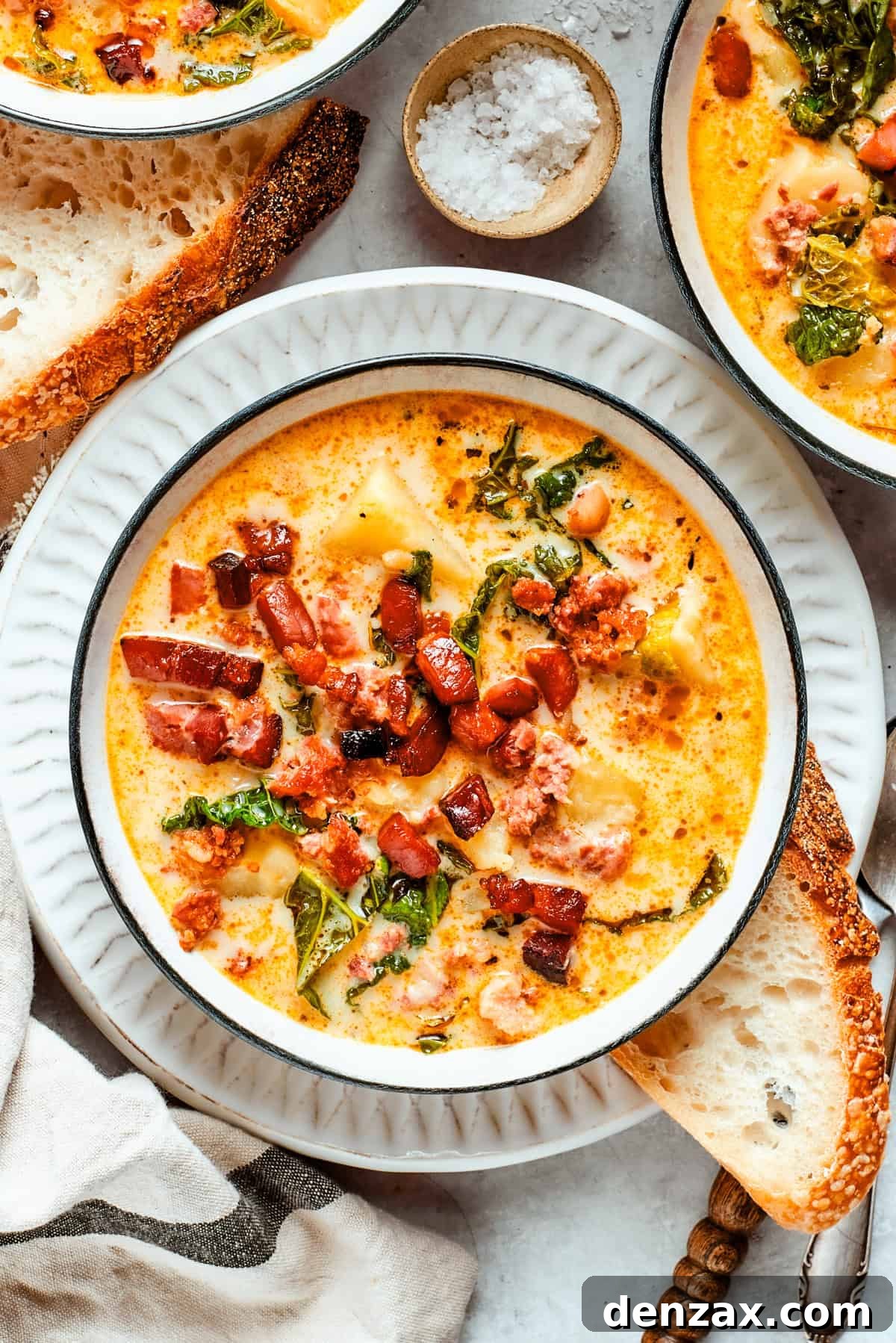 A bowl of Zuppa Toscana is served in bowls and garnished with crumbled bacon.