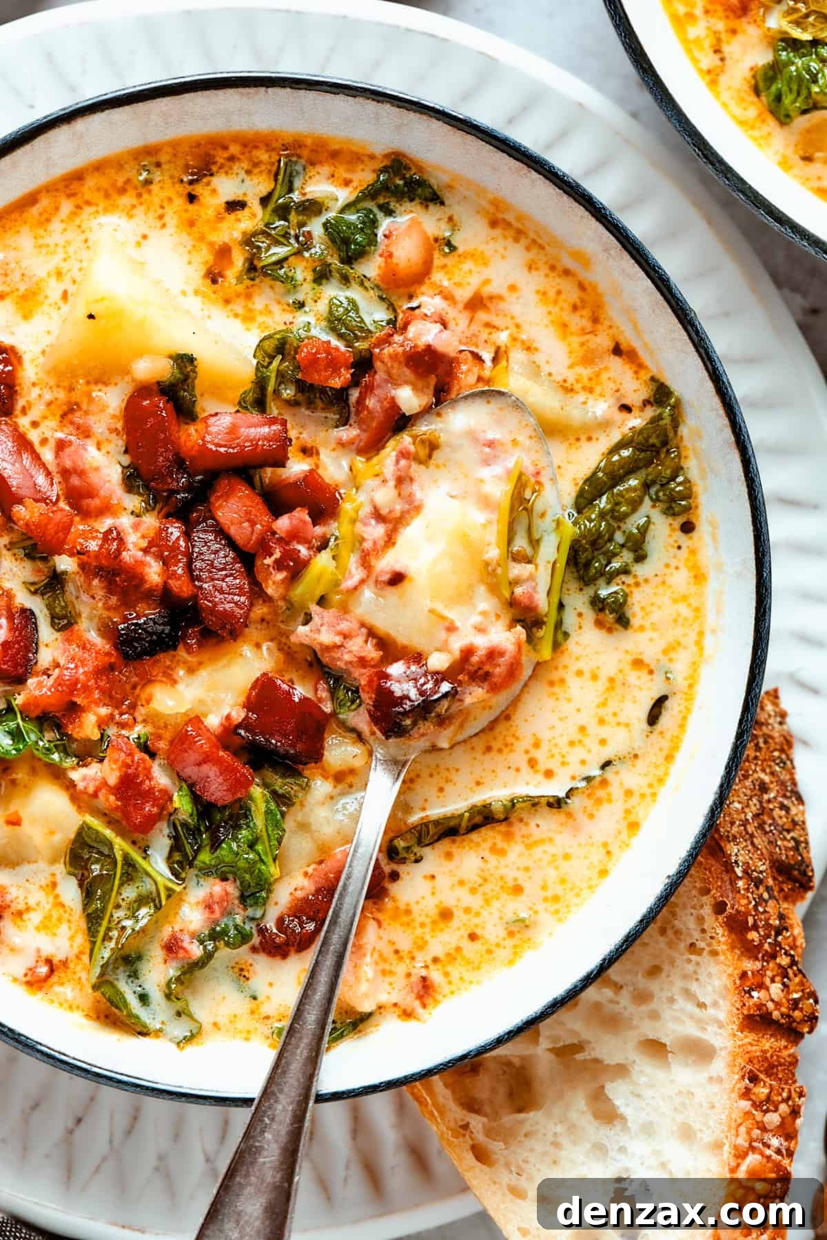 Close-up shot of Zuppa Toscana served in a bowl with a spoon placed inside it.