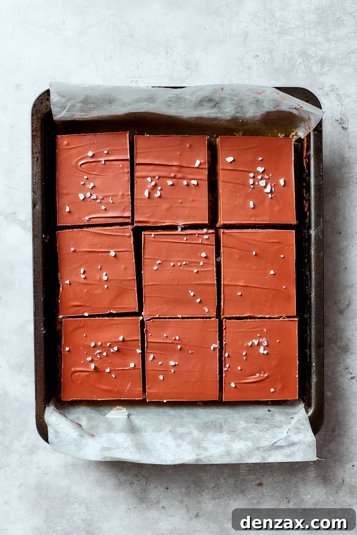 Chocolate ganache and flaky salt top a pan of millionaire bars.