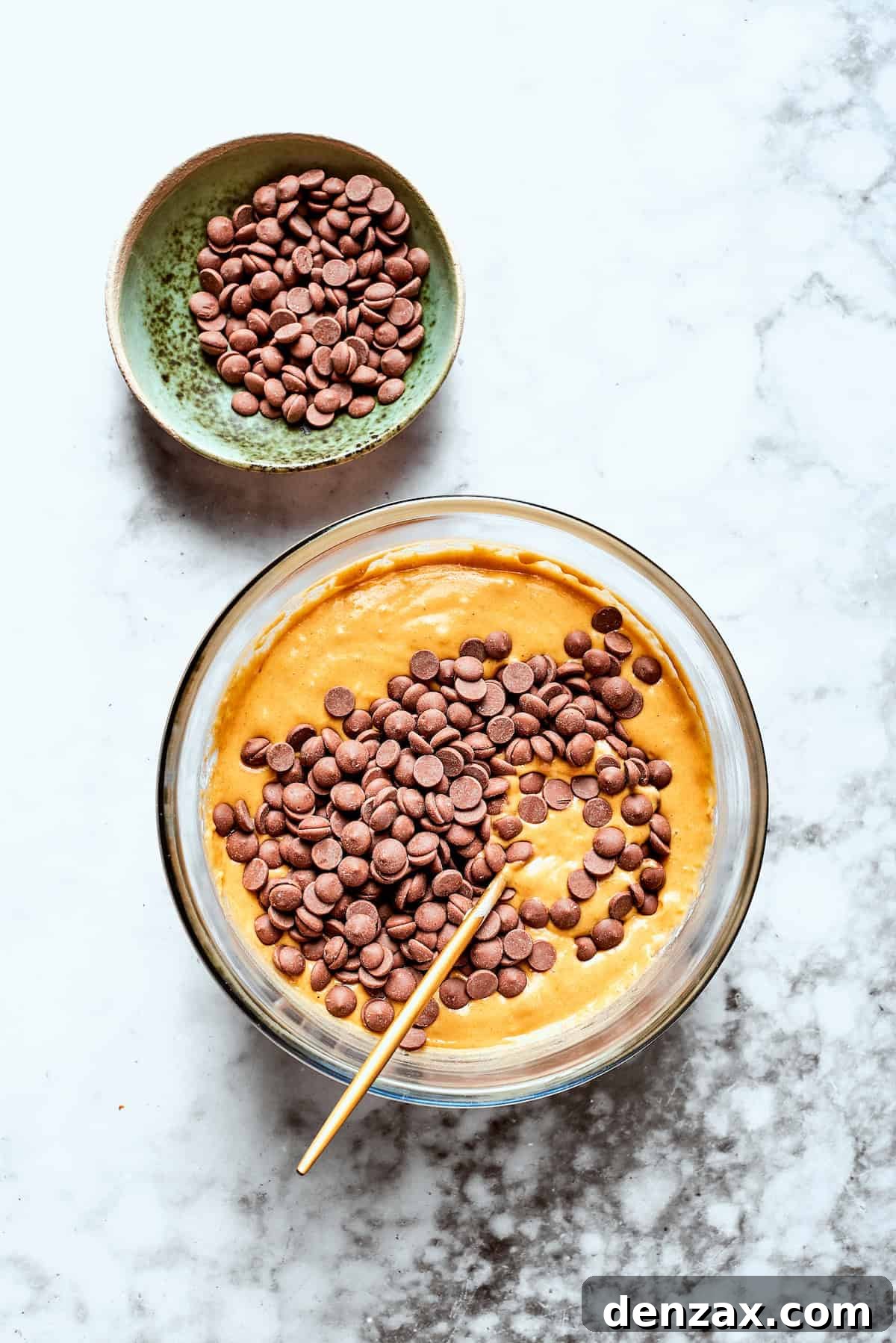 Warmly spiced Pumpkin Chocolate Chip Muffins are soft, fluffy, and loaded with chocolate chips in every bite! Chocolate chips are added to a bowl of pumpkin muffin batter.