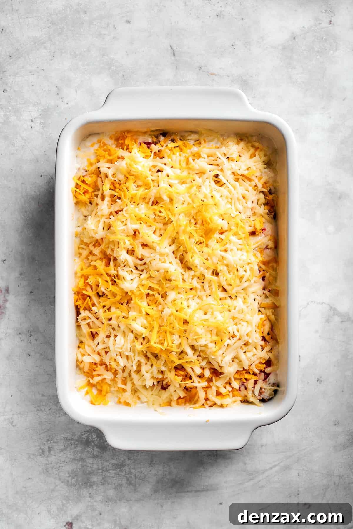 Sprinkle cheese on top. Cheese sprinkled on top of John Wayne Casserole ready to bake.