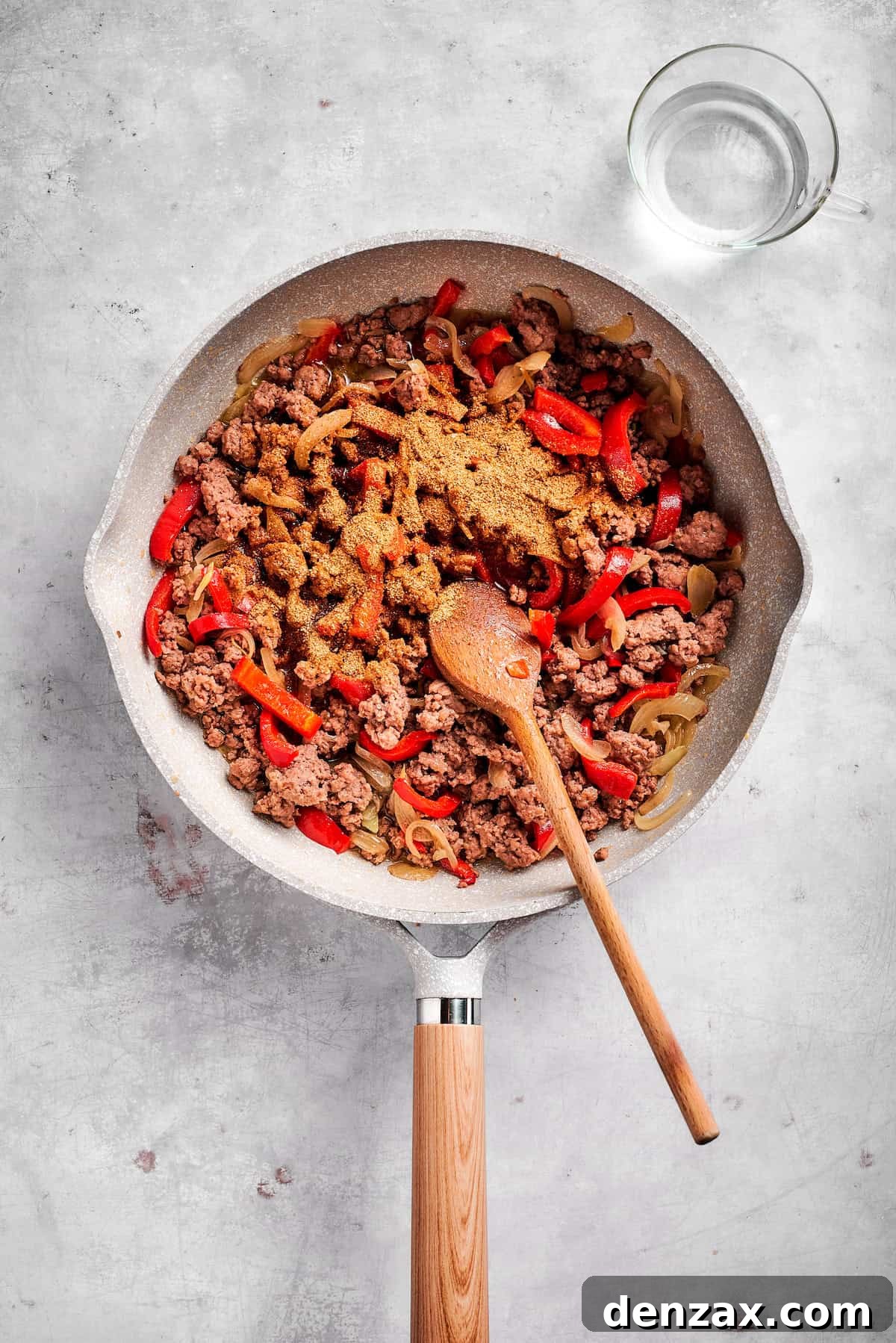 Add taco seasoning. Adding taco seasoning to cooked beef and peppers.