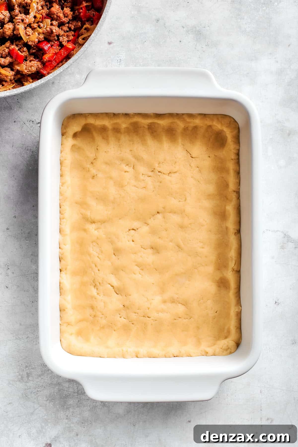 Press dough into the dish. Pressing dough into a baking dish.