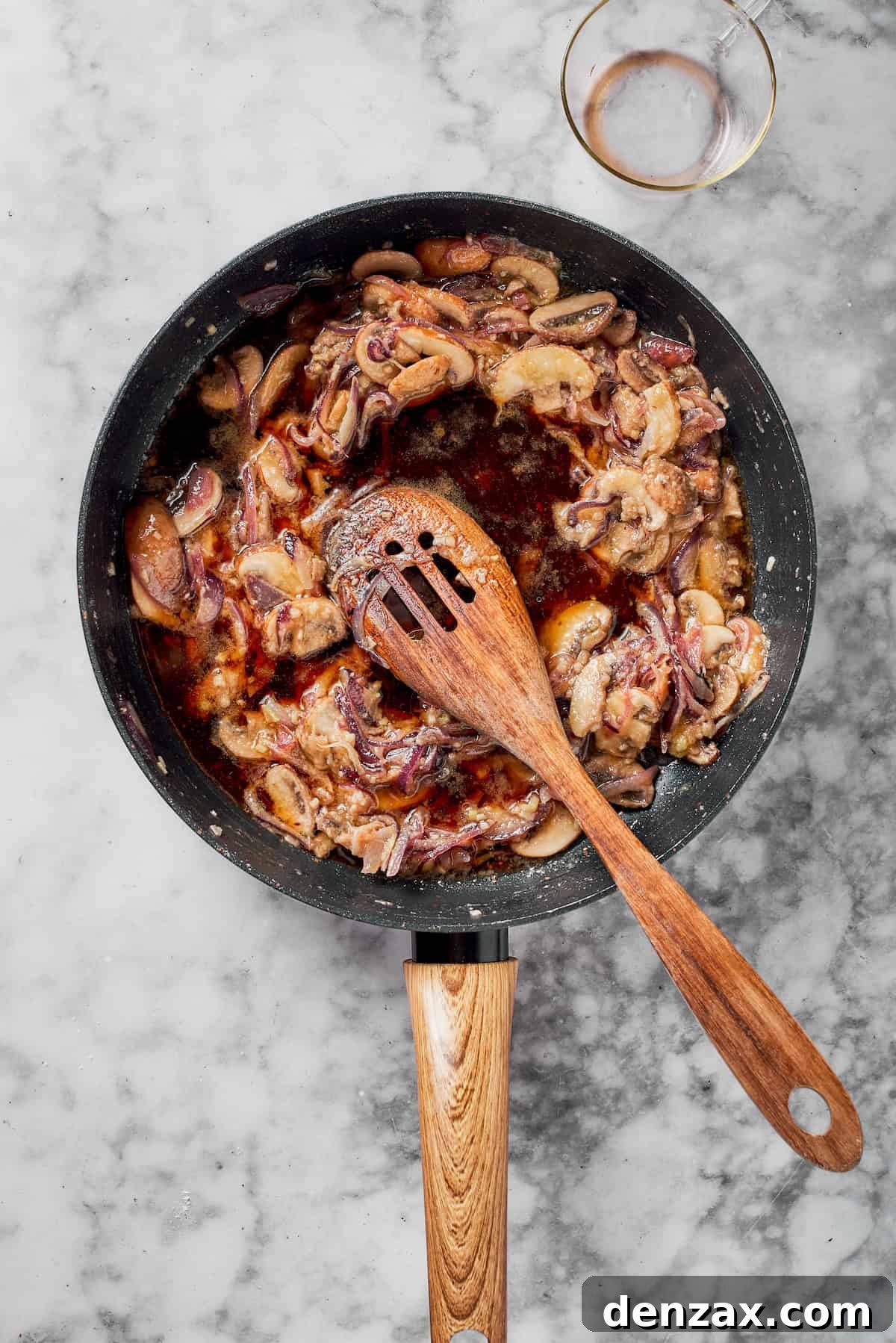Adding wine to mushrooms in a skillet.