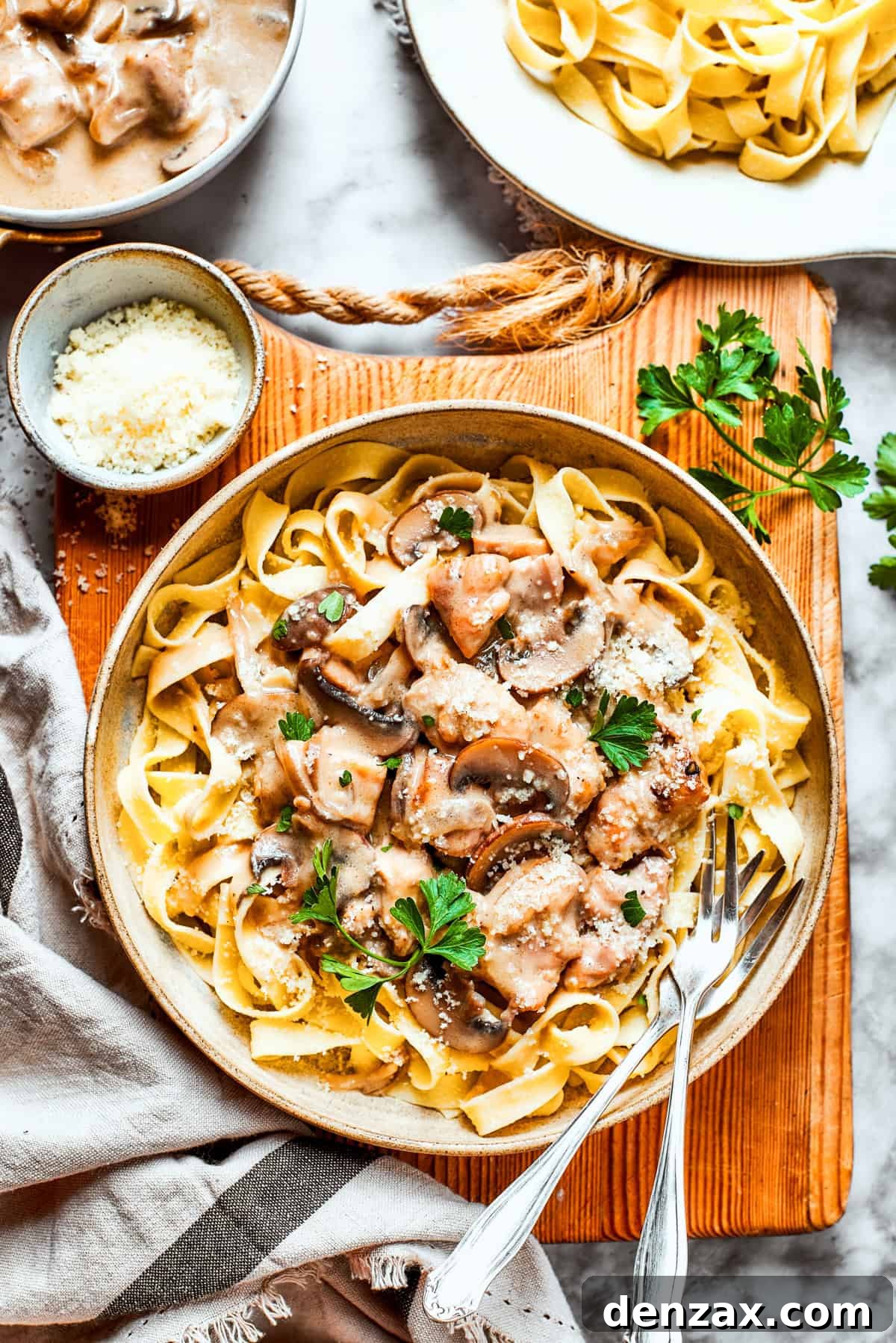 Bowl of chicken fettuccine placed on a wooden board.