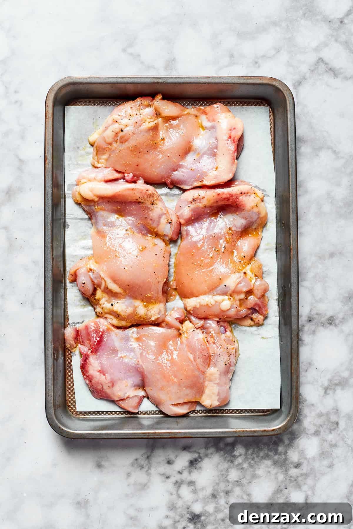 Raw chicken on a baking sheet ready to roast.