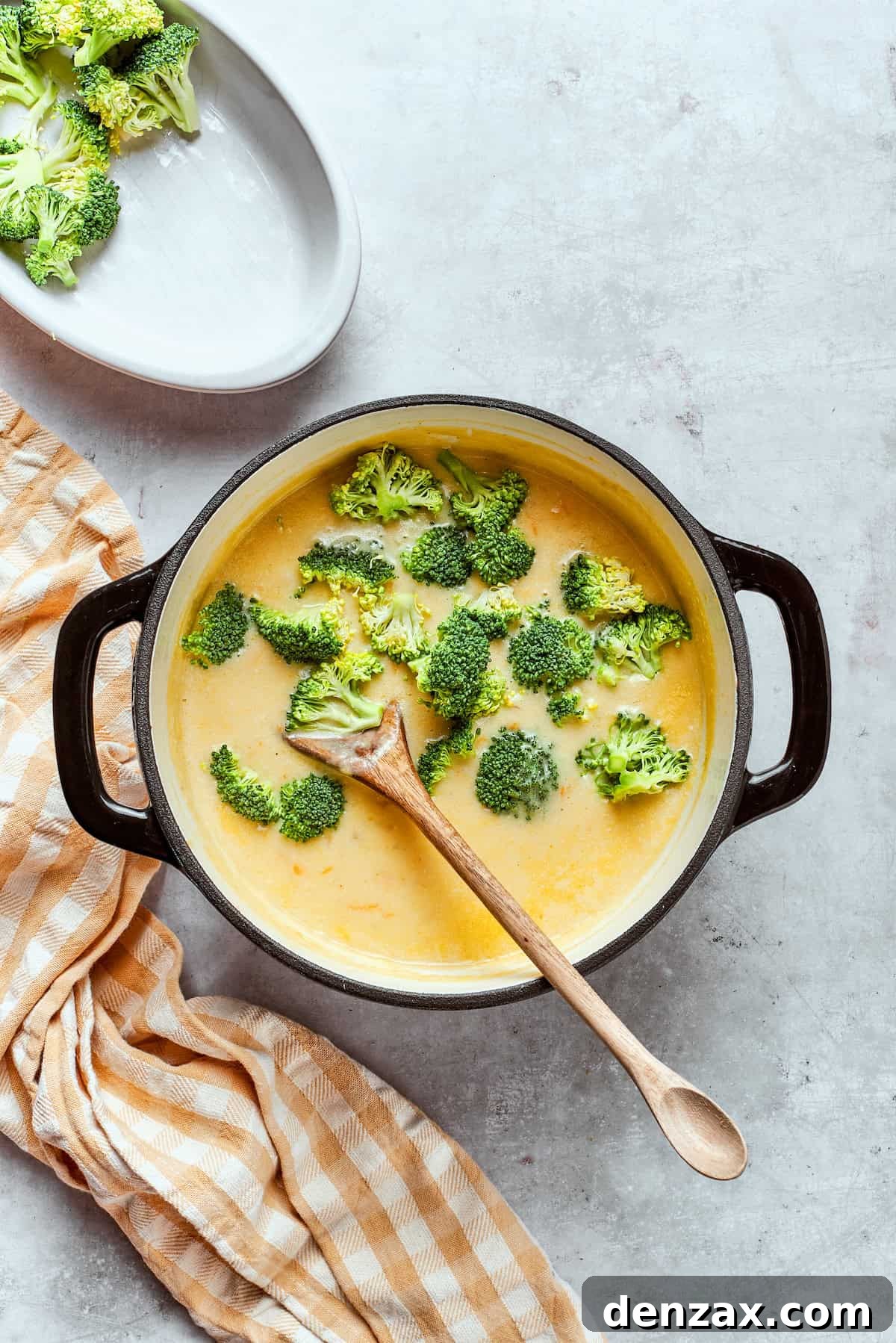 Stirring broccoli florets into a pot of soup.