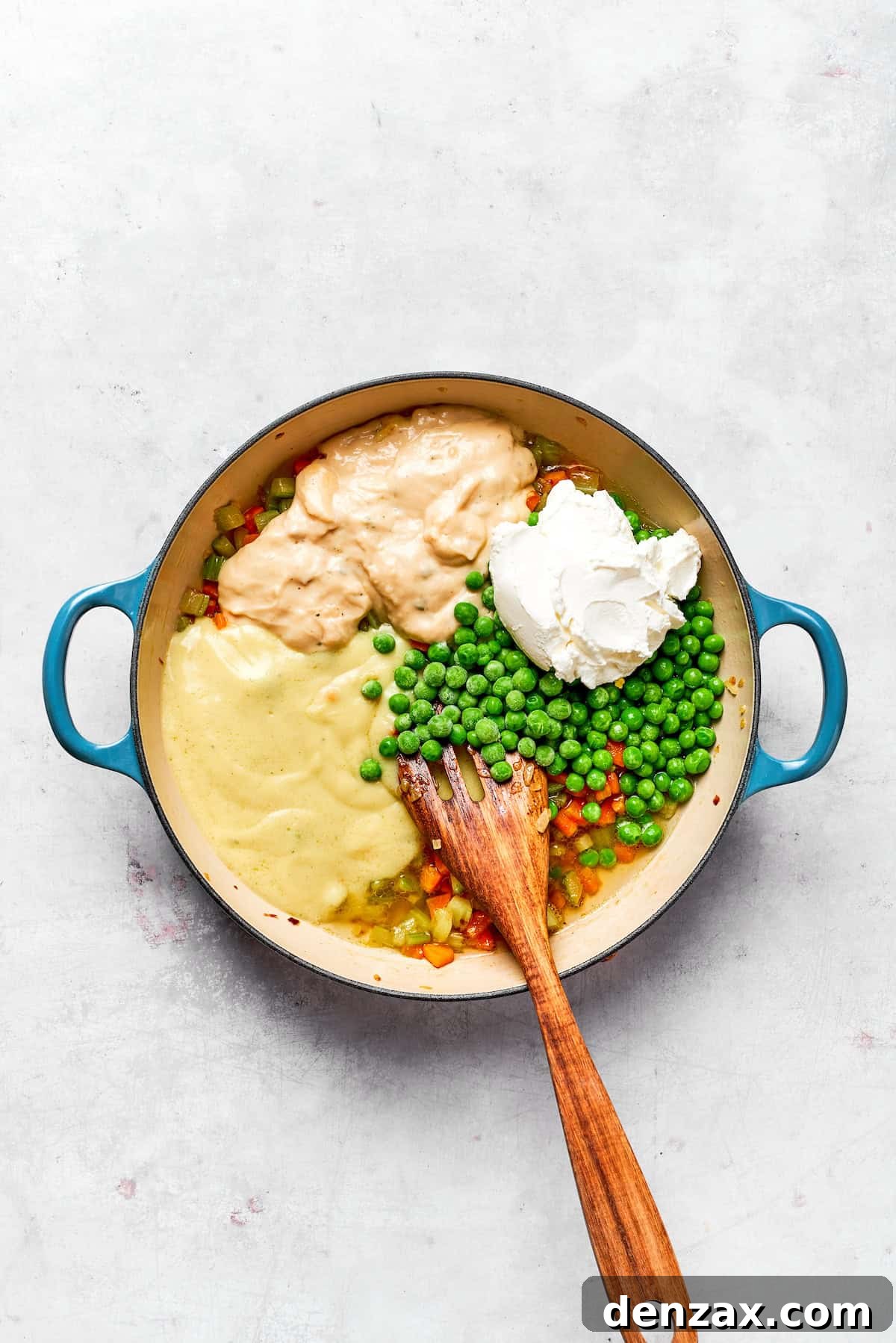 This chicken stuffing casserole features tender chicken filling with veggies topped with classic stuffing. An easy recipe baked until golden! Adding sour cream, condensed soups, and peas to a pot.