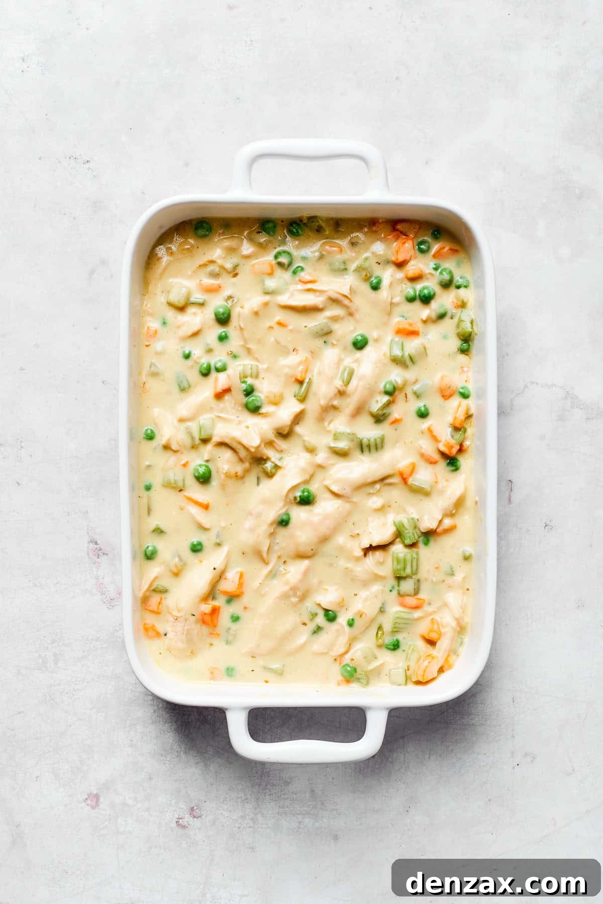 This chicken stuffing casserole features tender chicken filling with veggies topped with classic stuffing. An easy recipe baked until golden! Creaming chicken filling in a baking dish.