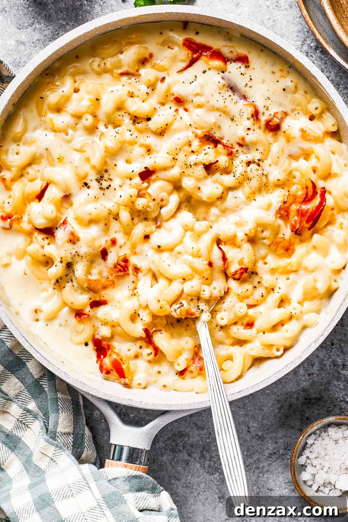 A skillet with mac and cheese and bacon stirred in.