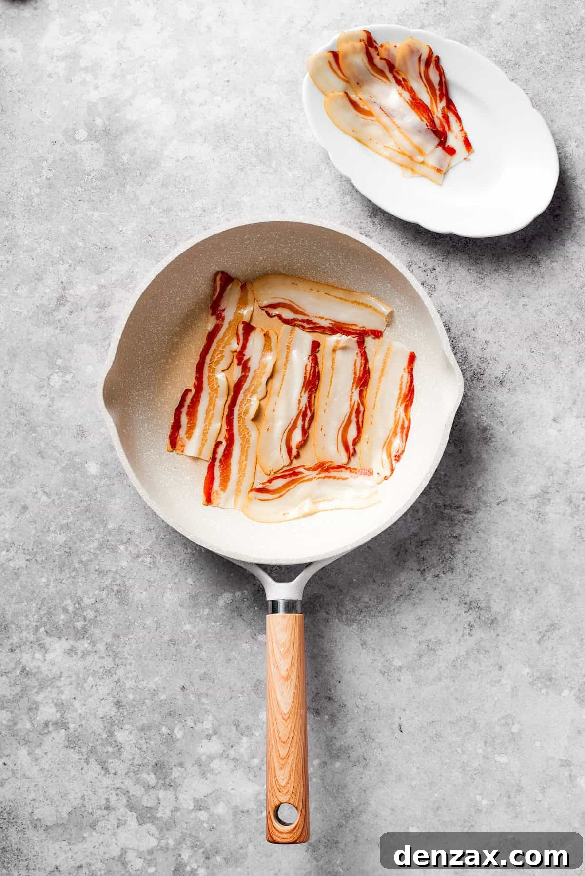 Bacon fries in a skillet.
