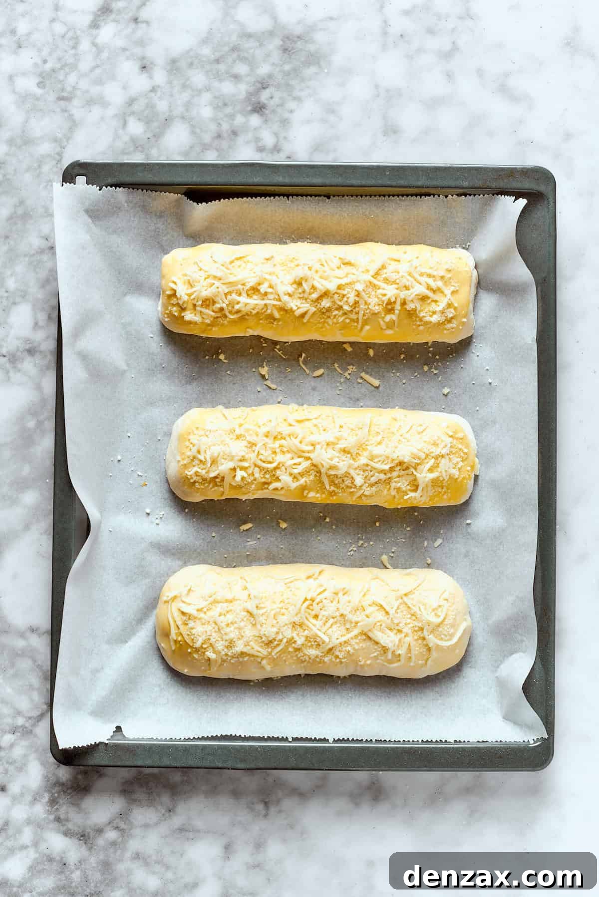 Three Costco chicken bake rolls on a baking sheet.