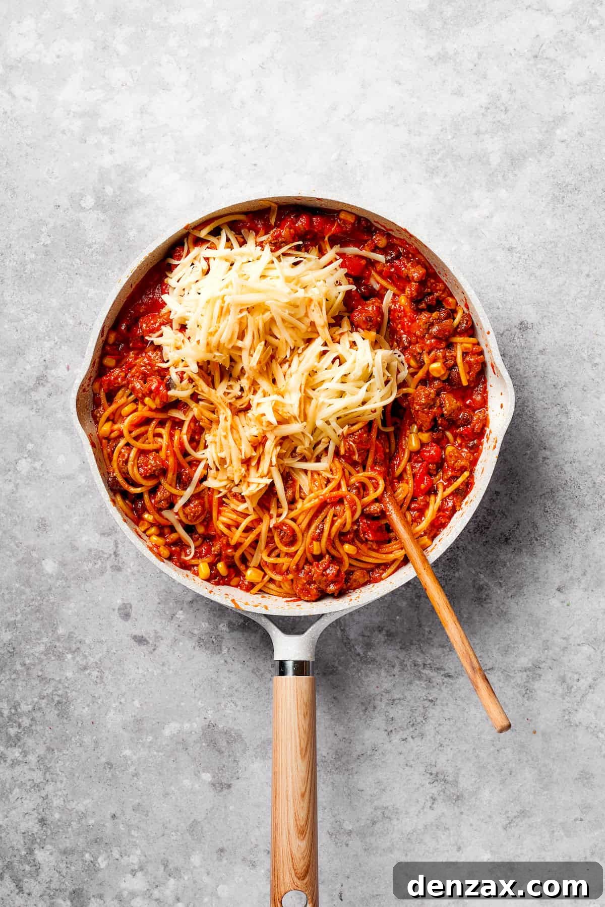 Cheeses are mixed into a pan of Mexican spaghetti.