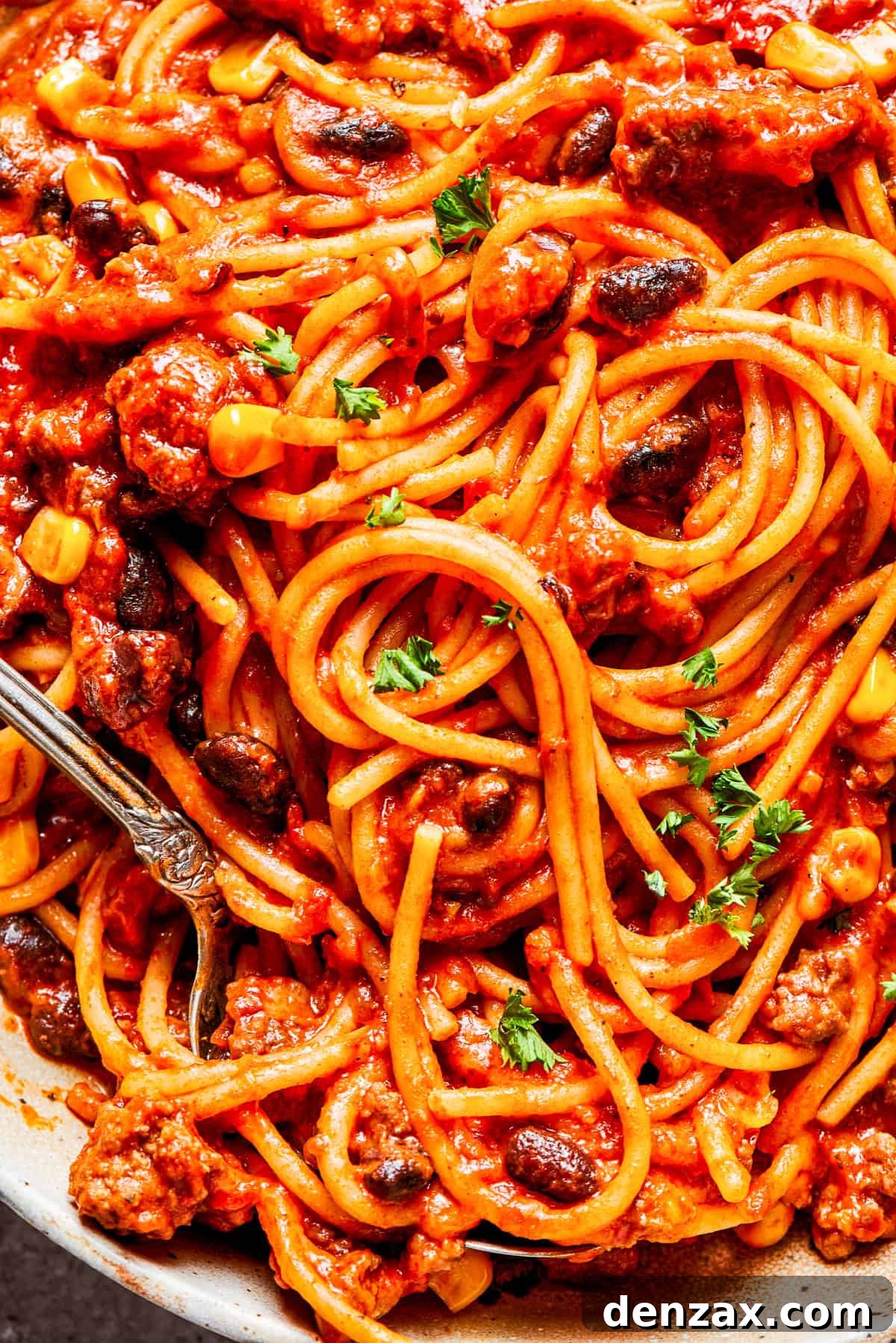 Close-up image of cooked Mexican spaghetti tossed with tomato sauce and beans.