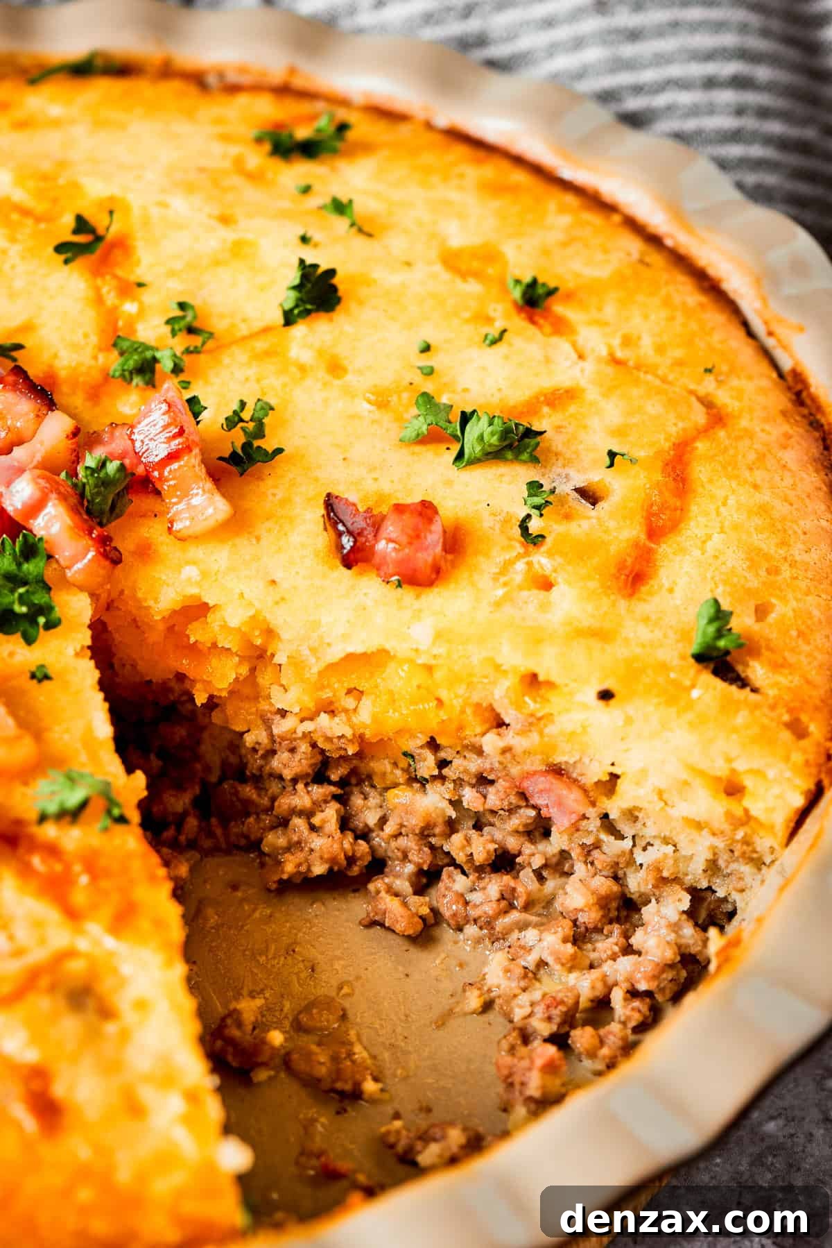 Close-up photo of a cheeseburger pie with a piece of pie cut out to expose the ground meat.