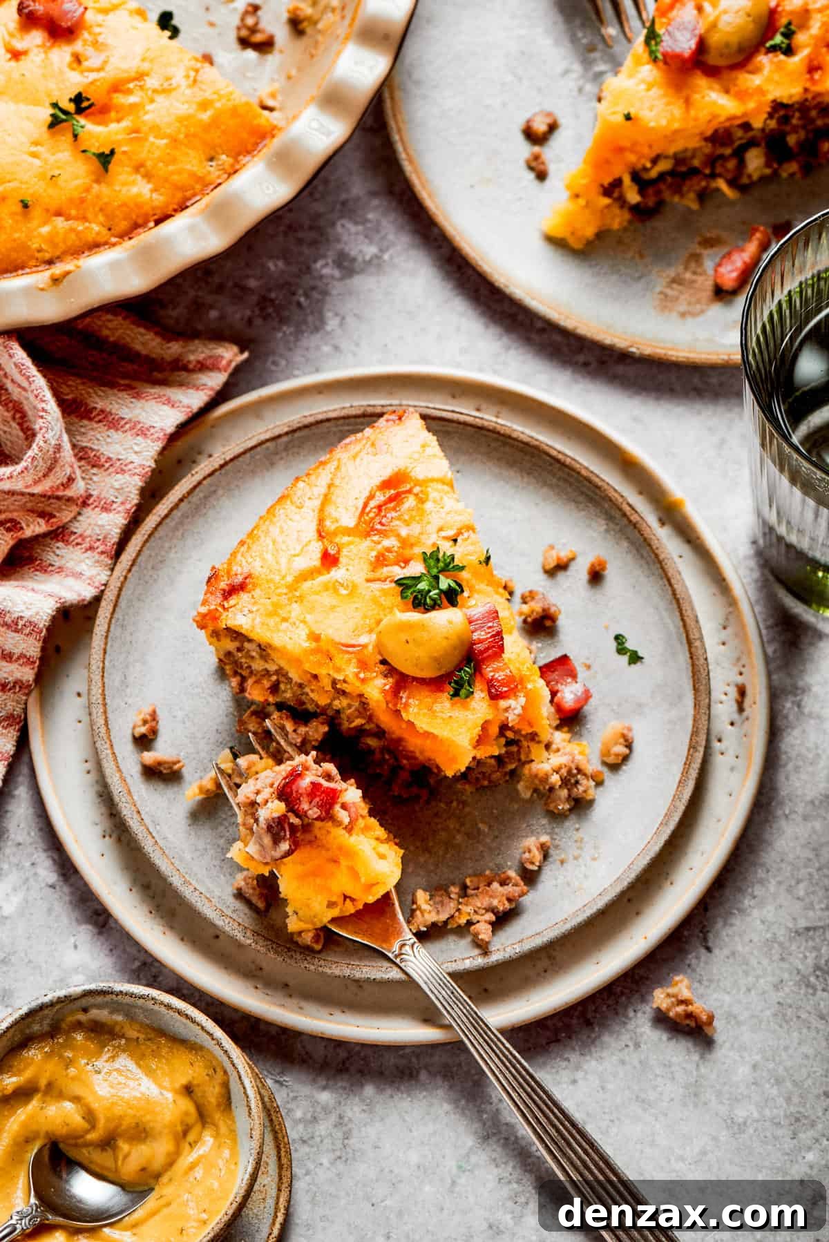 A slice of cheeseburger pie served on a dinner plate, with a fork set next to the slice of pie.