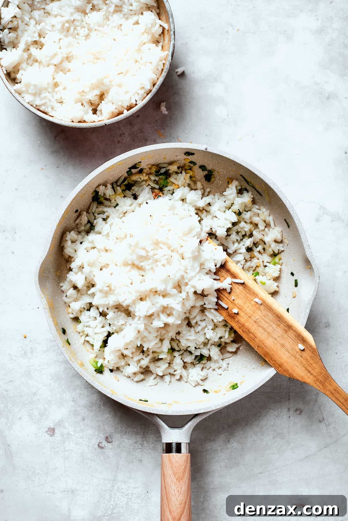 White rice is stirred into a pan for fried rice.