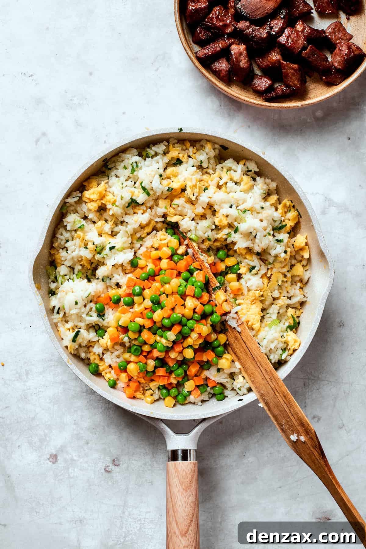 Veggies are added to fried rice.