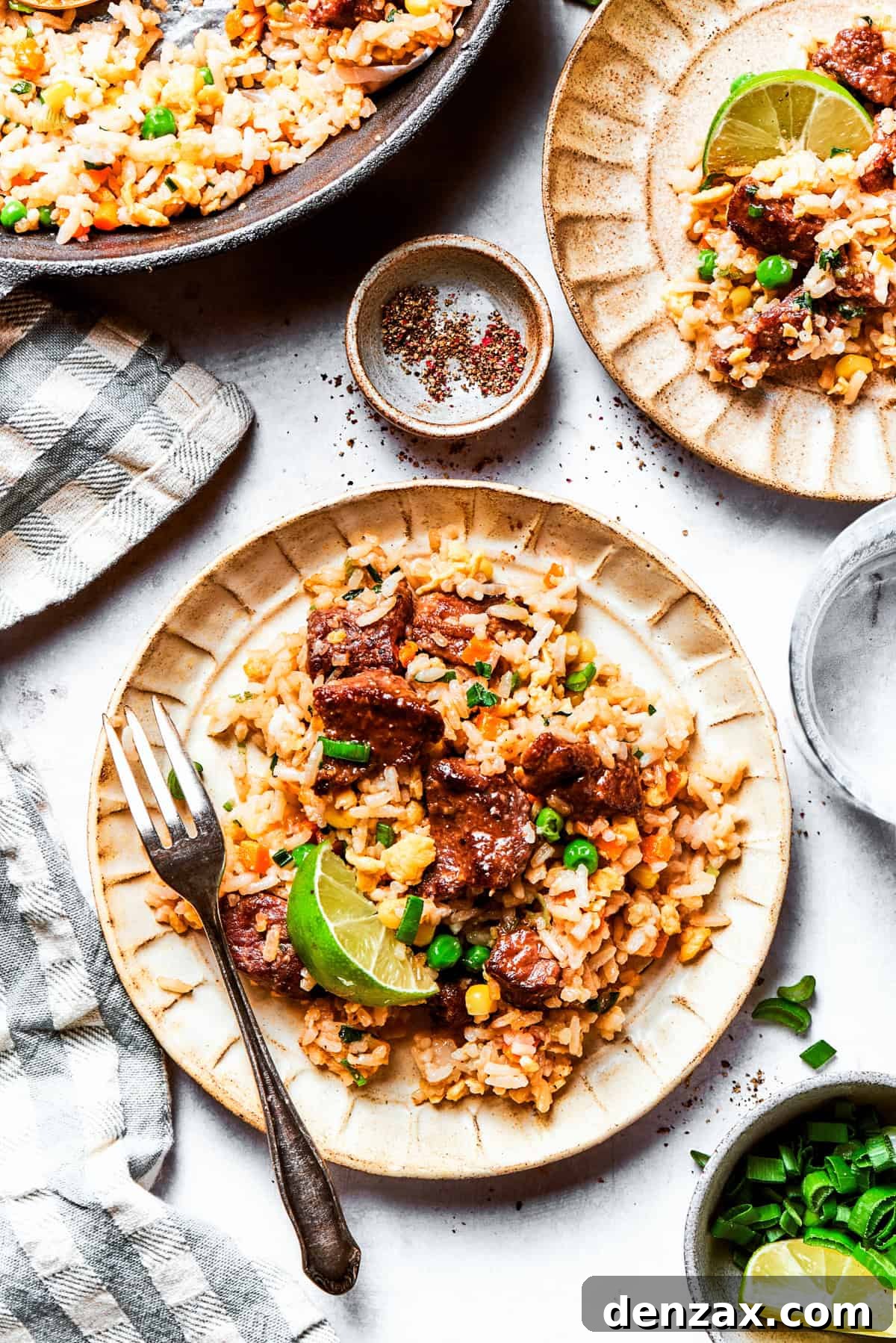 Steak fried rice served on a dinner plate with a fork.