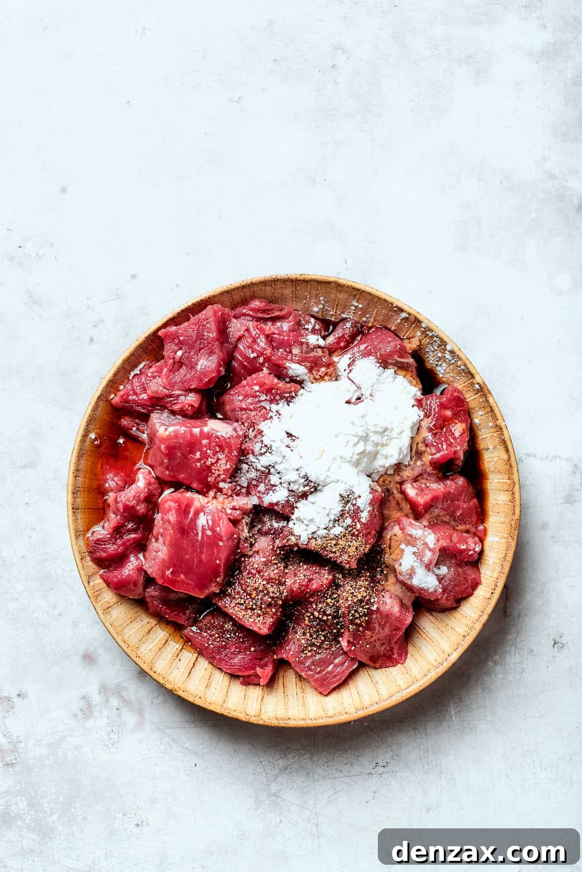 Cubes of steak are mixed with cornstarch and baking soda.