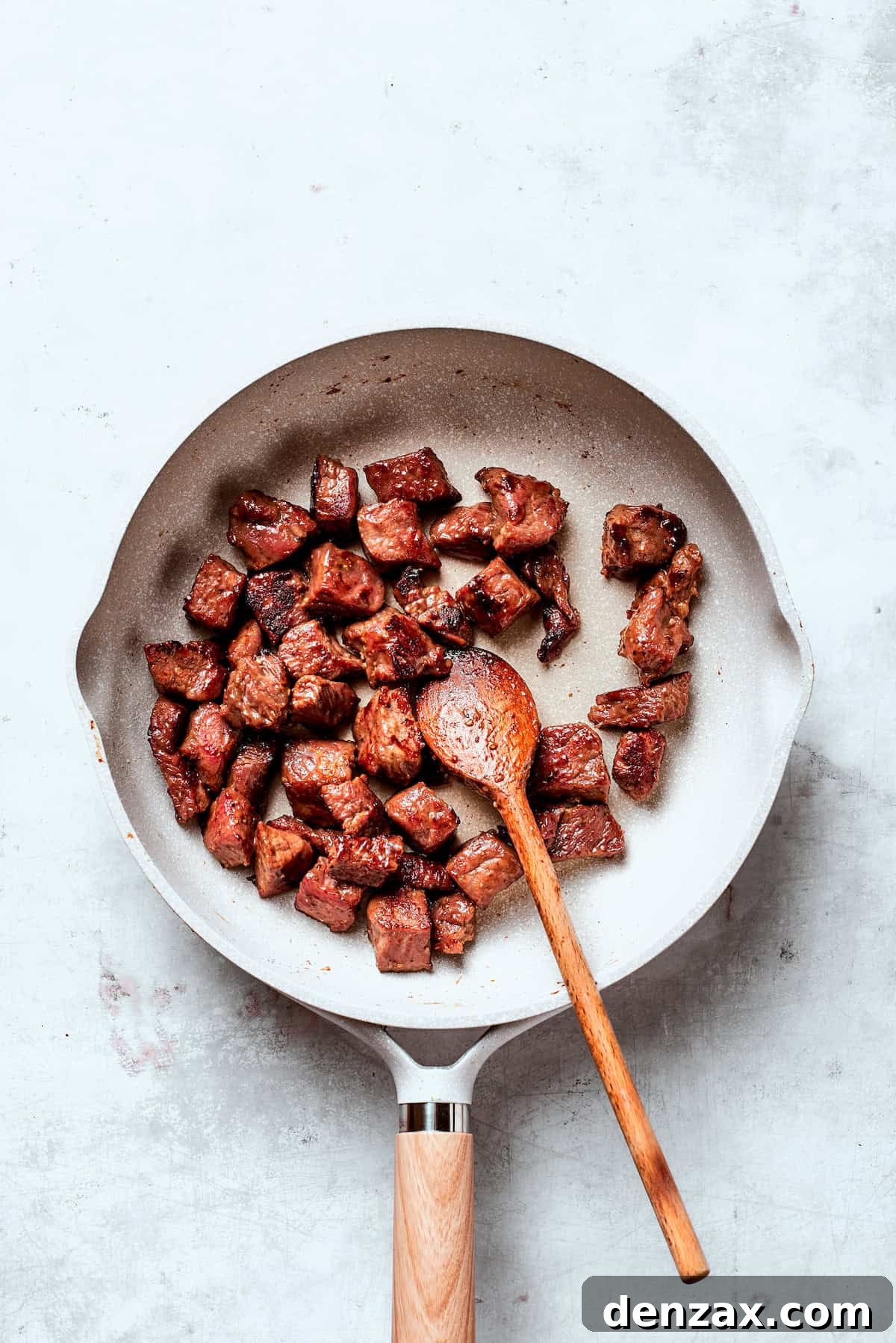 Cubes of steak cooked in a pan.