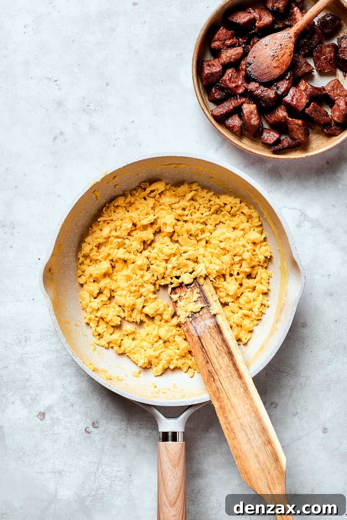 Eggs are stirred as they cook in a pan.