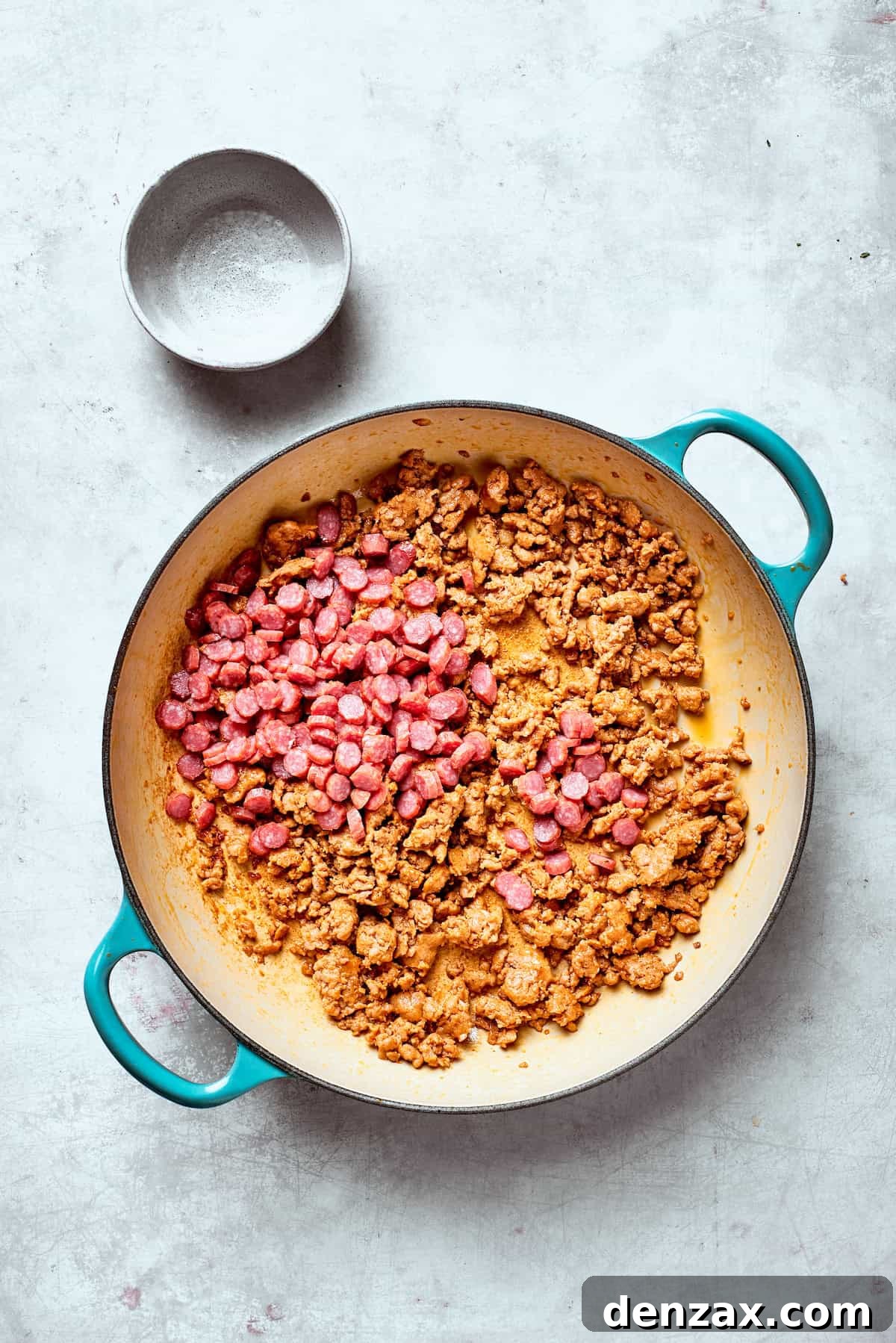 Pepperoni is added to a pan of browned sausage.