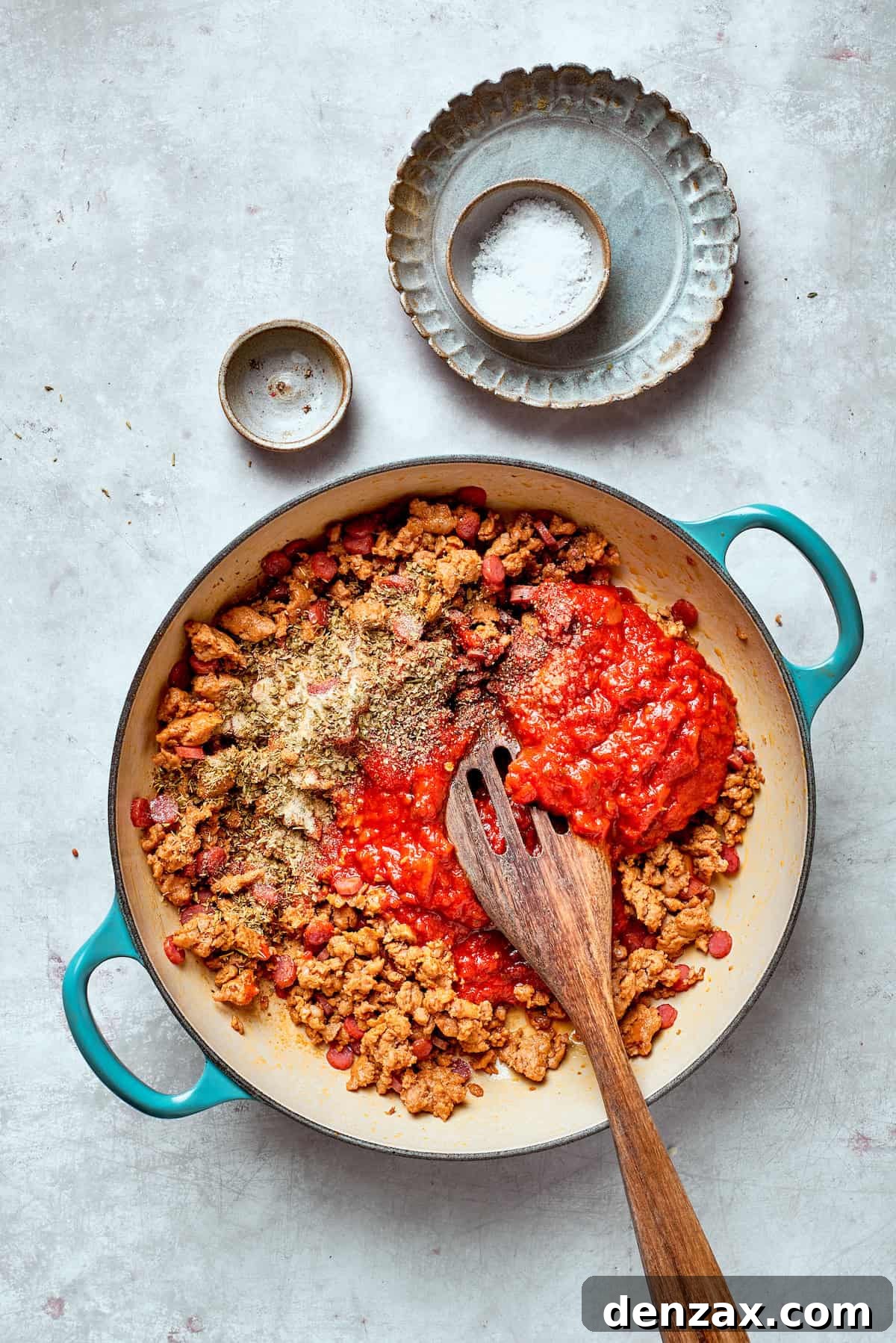 Tomato sauce is stirred into a pan.