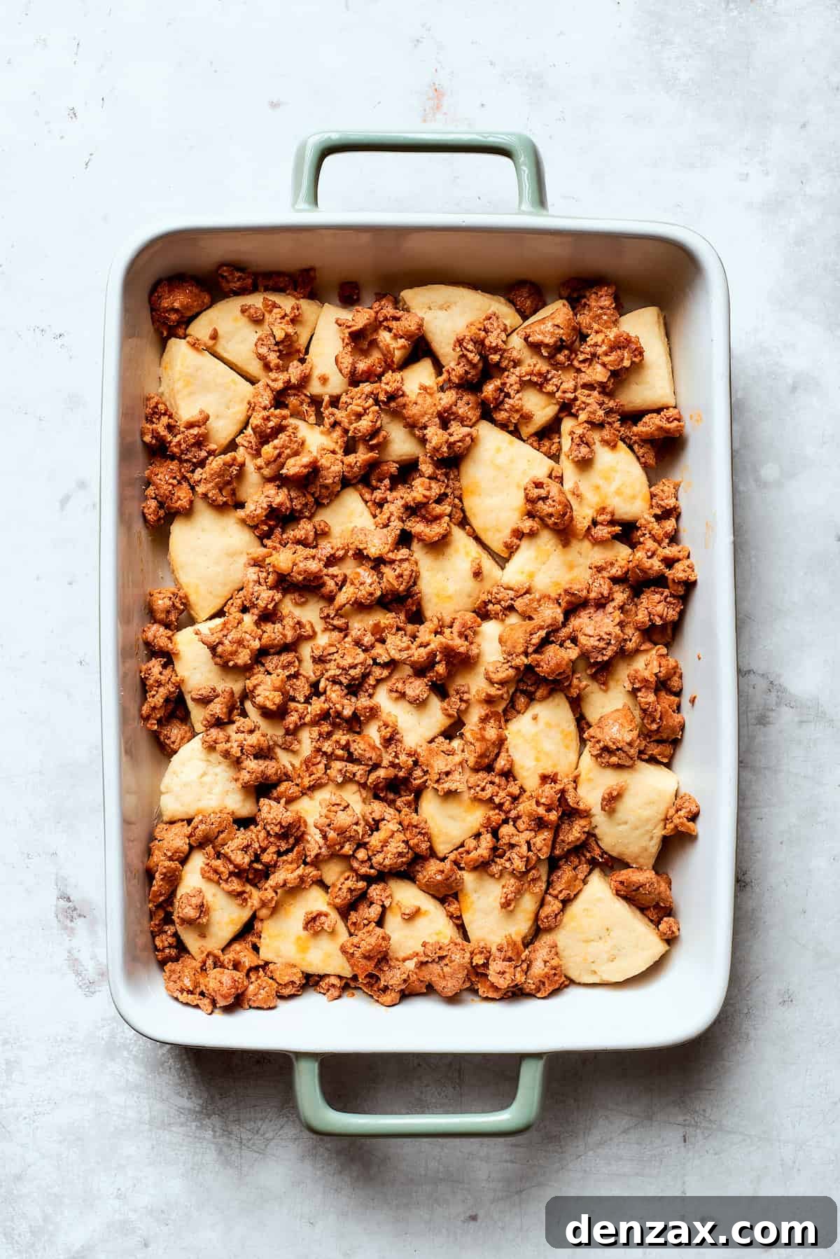 Browned sausage placed on top of biscuit dough pieces.