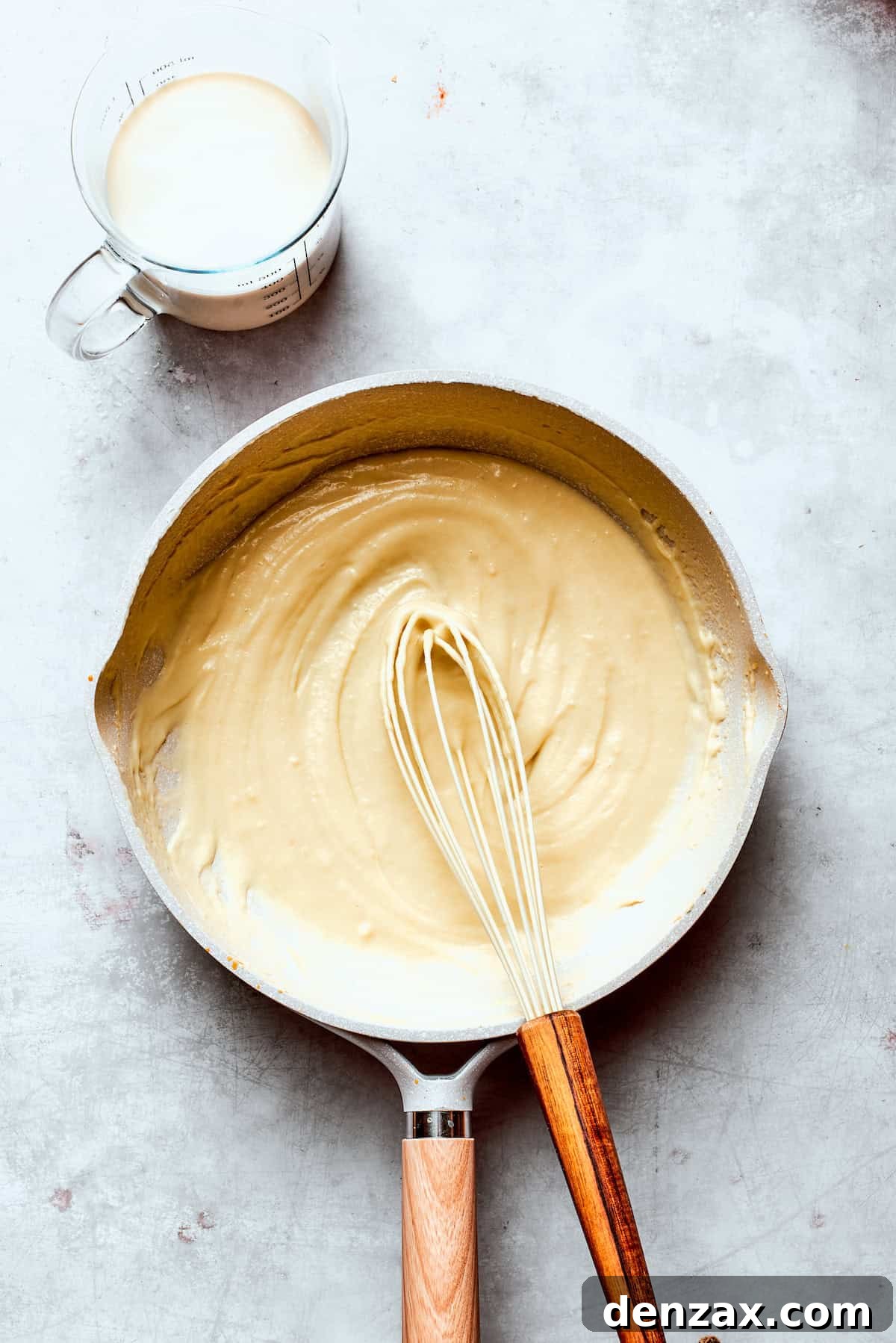Milk is whisked into a skillet of roux.