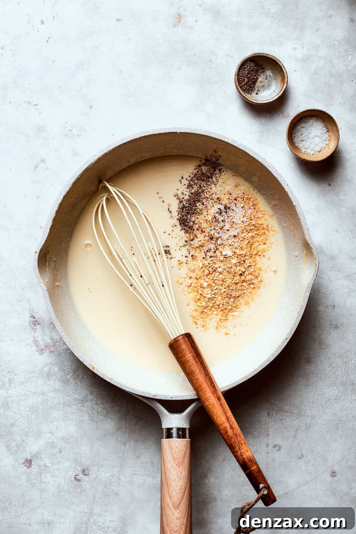 Seasonings are added to gravy in a skillet.